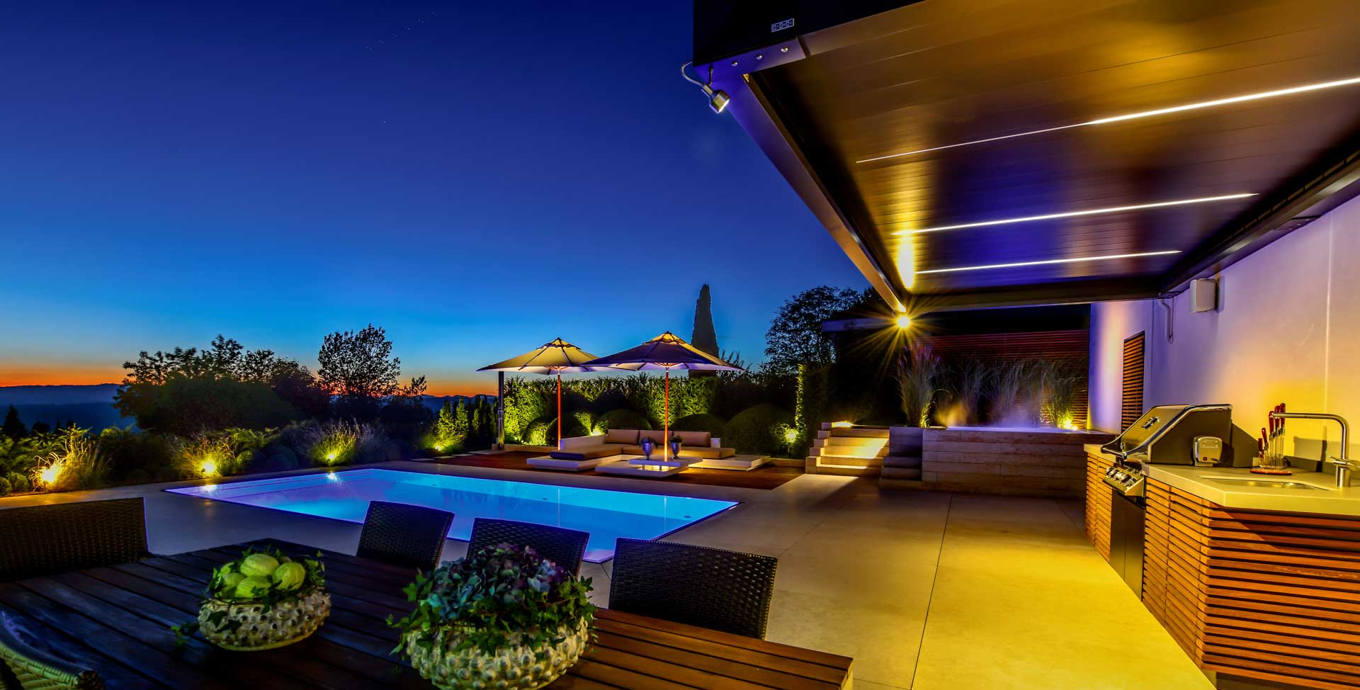 Terrasse bei Nacht, Pool und Grillbereich wird mit Megaspot und Maxispot beleuchtet 